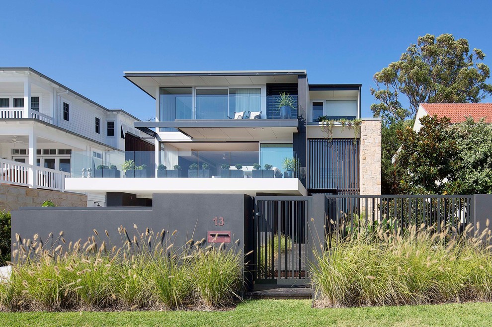 This is an example of a large contemporary two-storey house exterior in Sydney with stone veneer and a flat roof.