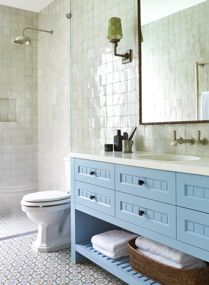 Inspiration for a mid-sized beach style master bathroom in Melbourne with recessed-panel cabinets, blue cabinets, a corner shower, a one-piece toilet, white tile, mosaic tile, white walls, mosaic tile floors, a drop-in sink, engineered quartz benchtops, white floor and an open shower.