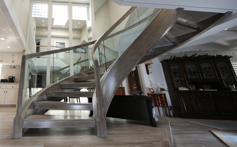 Large modern wood curved staircase in Orange County with open risers.