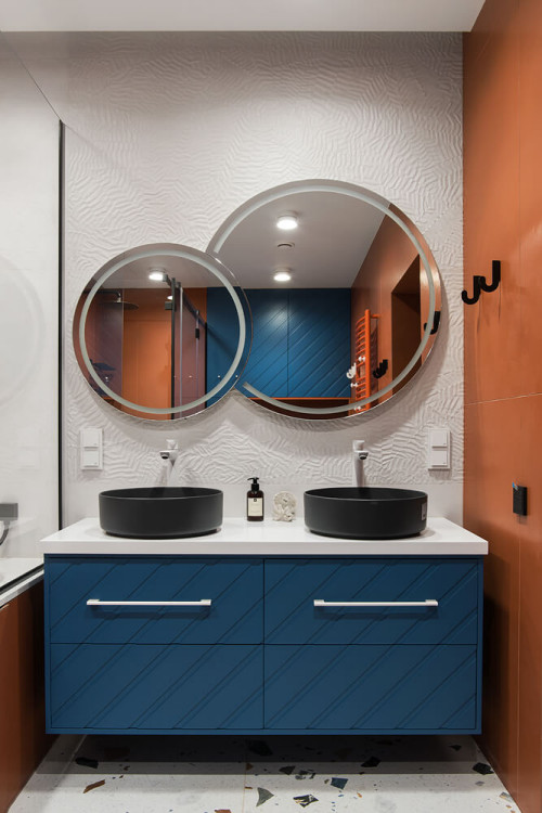Blue Vanity with Black Vessel Sinks and Round Mirrors