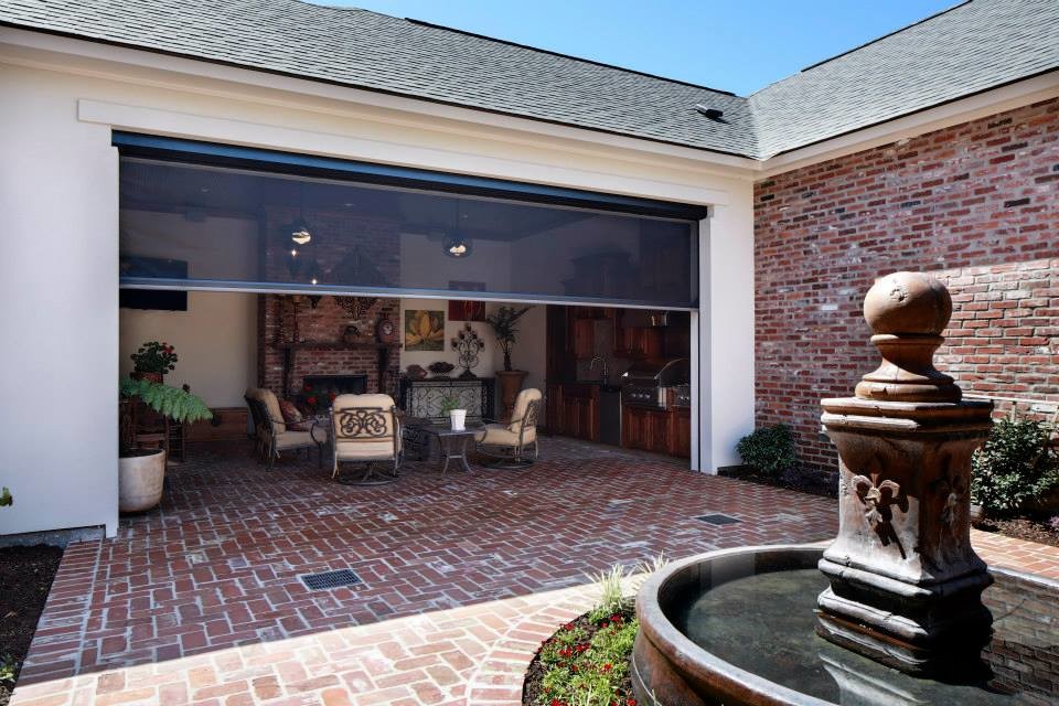 This is an example of a mid-sized traditional courtyard patio in New Orleans with a water feature, brick pavers and a roof extension.