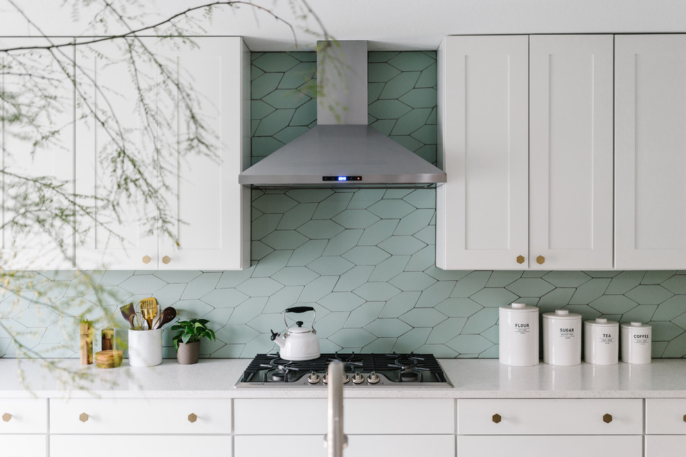 This is an example of a large modern l-shaped eat-in kitchen in Austin with a farmhouse sink, shaker cabinets, white cabinets, quartz benchtops, green splashback, stone tile splashback, stainless steel appliances and with island.