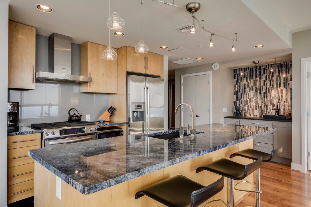 Small transitional galley light wood floor open concept kitchen photo in Austin with a double-bowl sink, flat-panel cabinets, light wood cabinets, granite countertops, gray backsplash, porcelain backsplash, stainless steel appliances and an island
