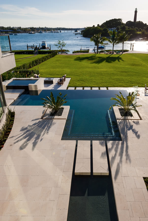 Design ideas for a mid-sized contemporary backyard custom-shaped infinity pool in Miami with a hot tub and tile.