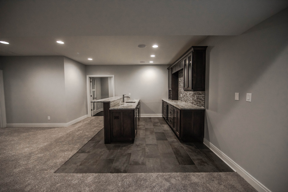 Design ideas for a large traditional look-out basement in Indianapolis with a home bar, grey walls, carpet and brown floor.