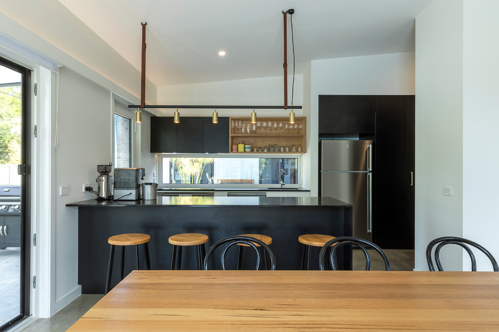 Small contemporary galley eat-in kitchen in Canberra - Queanbeyan with a drop-in sink, raised-panel cabinets, black cabinets, quartz benchtops, window splashback, stainless steel appliances, concrete floors, with island, grey floor and black benchtop.
