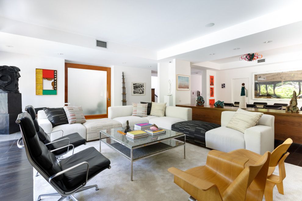 This is an example of a contemporary open concept living room in Los Angeles with white walls and black floor.