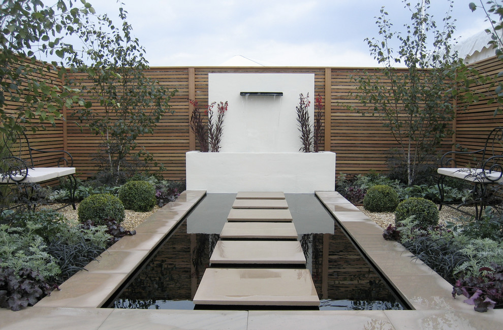 Inspiration for a contemporary full sun garden in Other with with pond and concrete pavers.