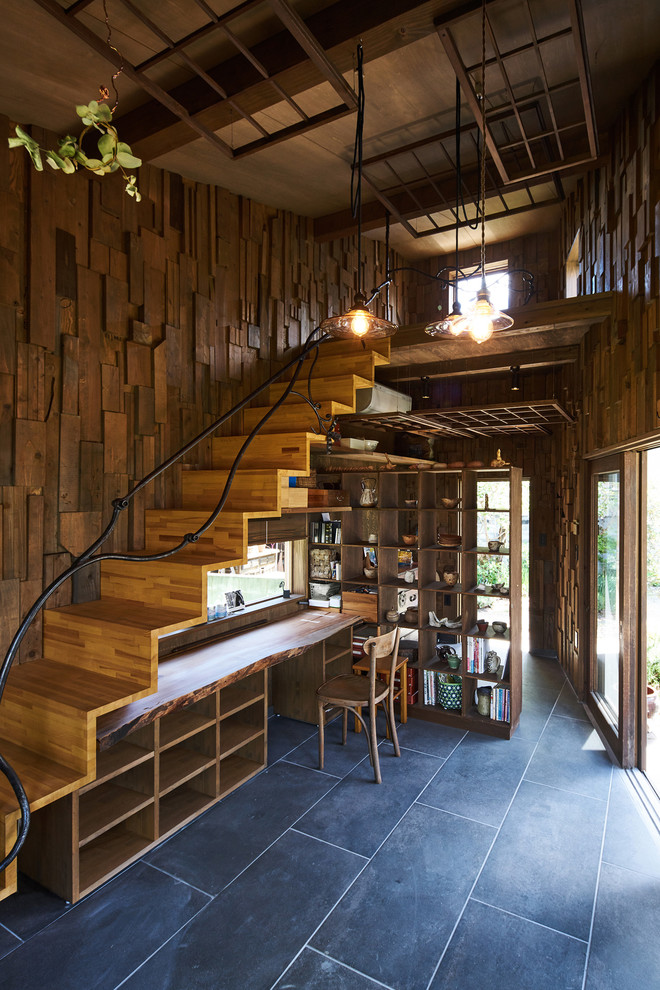 This is an example of a country home office in Other with brown walls, a built-in desk and black floor.