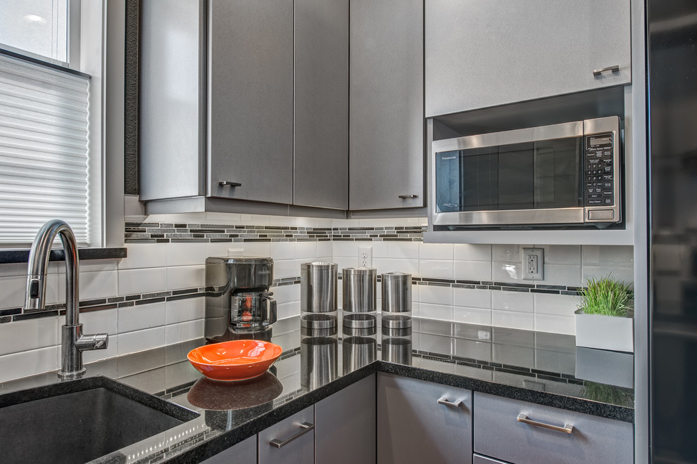 Inspiration for a small contemporary u-shaped eat-in kitchen in Denver with an undermount sink, flat-panel cabinets, stainless steel cabinets, granite benchtops, white splashback, ceramic splashback, stainless steel appliances, vinyl floors and no island.