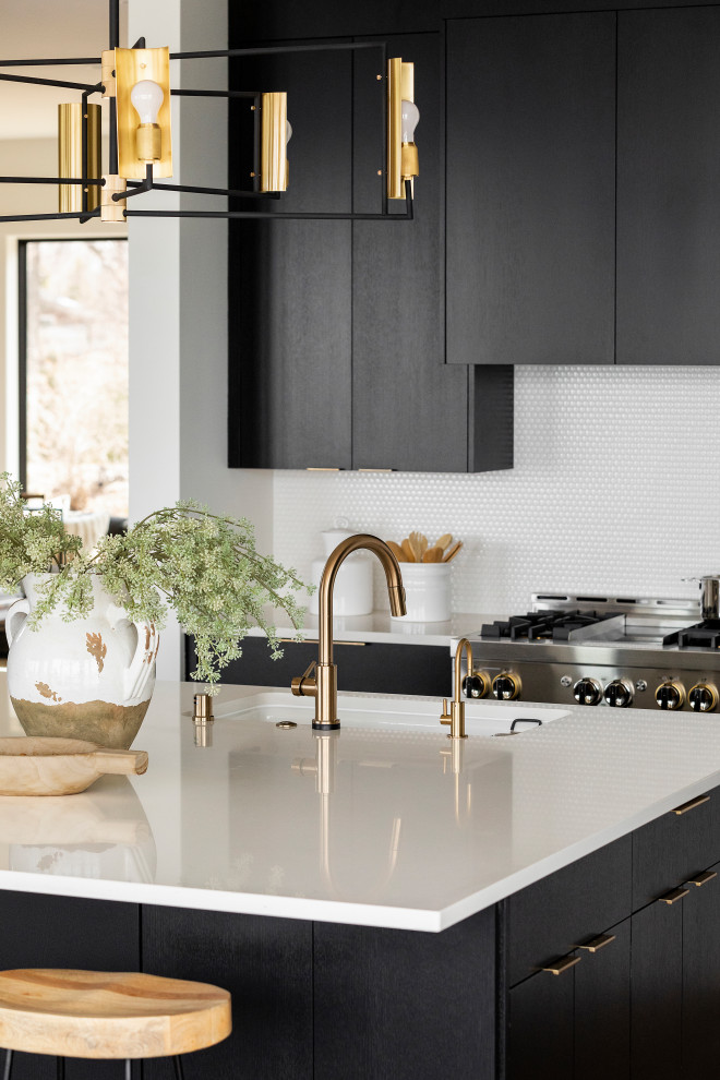 Inspiration for a large contemporary l-shaped eat-in kitchen in Minneapolis with a farmhouse sink, flat-panel cabinets, black cabinets, granite benchtops, white splashback, ceramic splashback, stainless steel appliances, light hardwood floors, with island, brown floor and white benchtop.