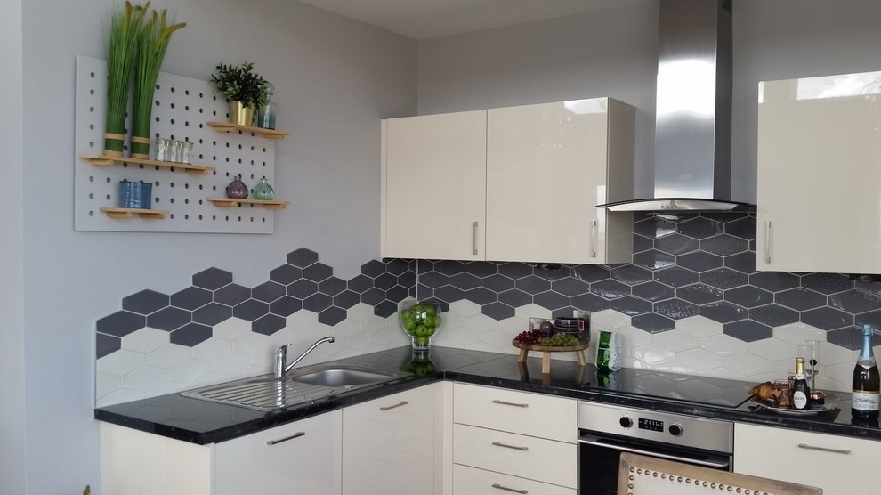 Mid-sized contemporary l-shaped eat-in kitchen in Dublin with a single-bowl sink, flat-panel cabinets, beige cabinets, laminate benchtops, grey splashback, porcelain splashback, stainless steel appliances, laminate floors and no island.