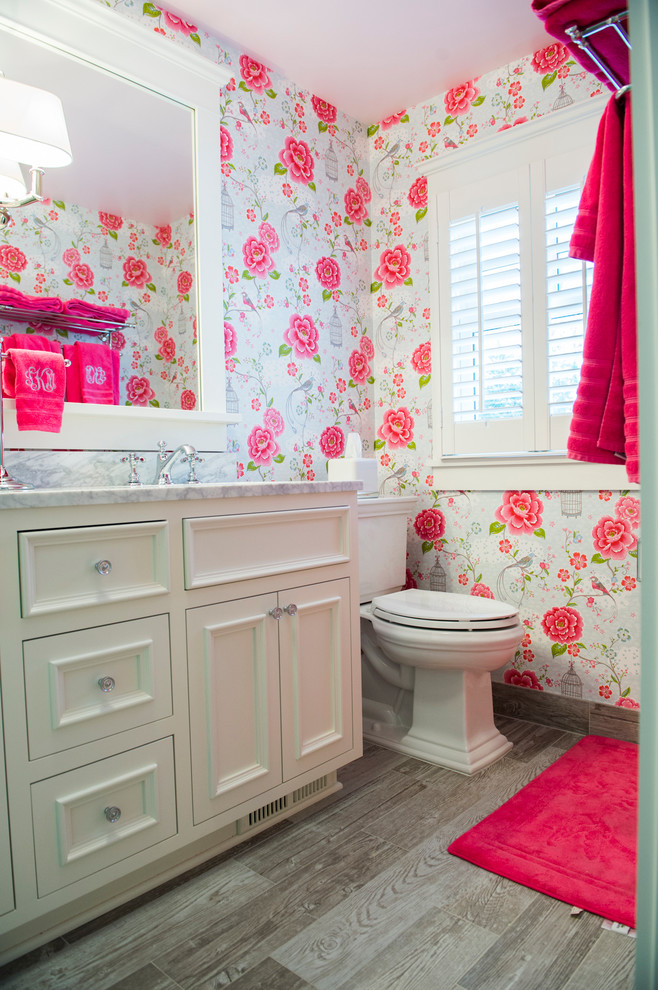 Inspiration for a mid-sized traditional kids bathroom in Minneapolis with an undermount sink, furniture-like cabinets, white cabinets, marble benchtops, a corner shower, gray tile, subway tile, pink walls, ceramic floors, a two-piece toilet, brown floor and a hinged shower door.