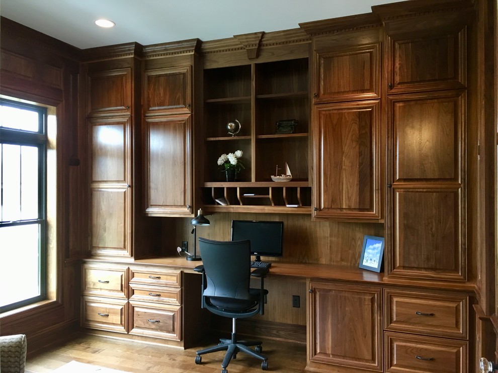 This is an example of a large transitional home office in Milwaukee with brown walls, medium hardwood floors, a built-in desk and brown floor.
