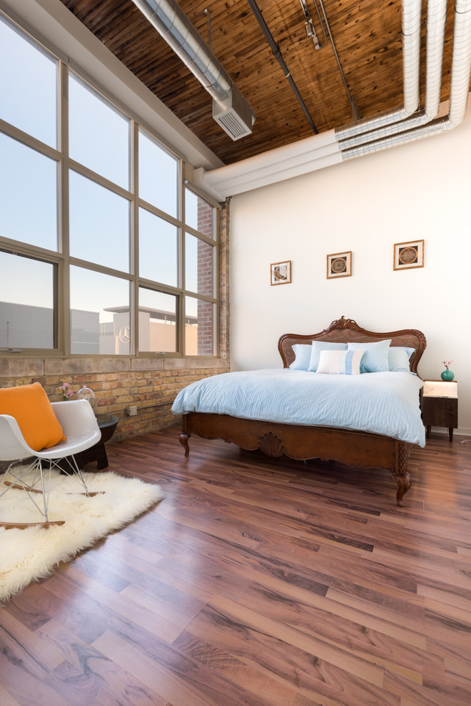 This is an example of a mid-sized industrial loft-style bedroom in Toronto with white walls and dark hardwood floors.