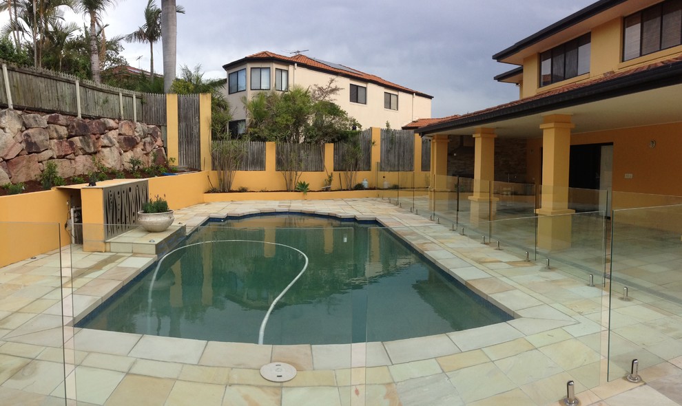 Photo of a large modern backyard rectangular natural pool in Brisbane with natural stone pavers.
