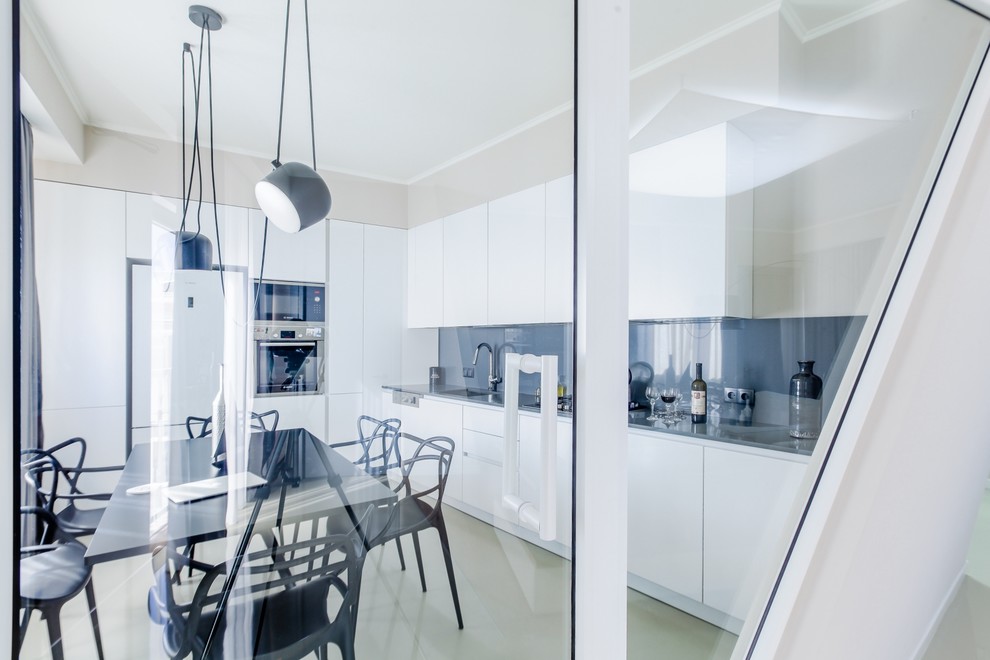 Photo of a mid-sized contemporary l-shaped eat-in kitchen in Other with a drop-in sink, open cabinets, white cabinets, granite benchtops, grey splashback, porcelain splashback, white appliances, concrete floors and no island.