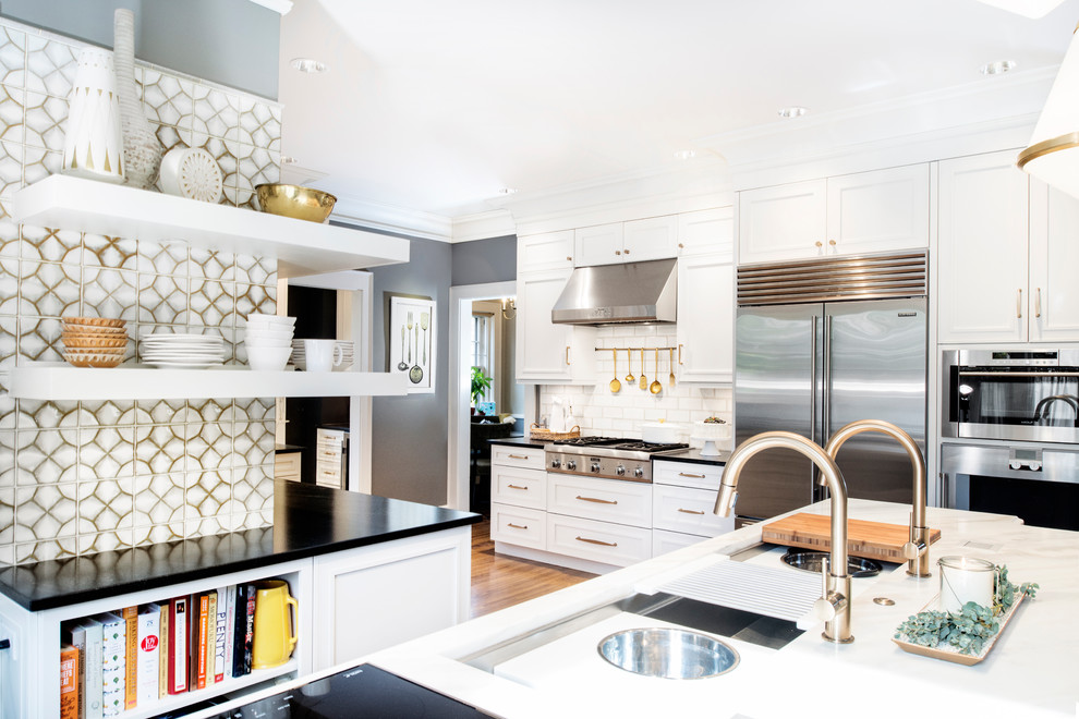 Inspiration for a large transitional u-shaped medium tone wood floor and brown floor eat-in kitchen remodel with marble countertops, white backsplash, glass tile backsplash, stainless steel appliances, an island, a farmhouse sink, recessed-panel cabinets and white cabinets