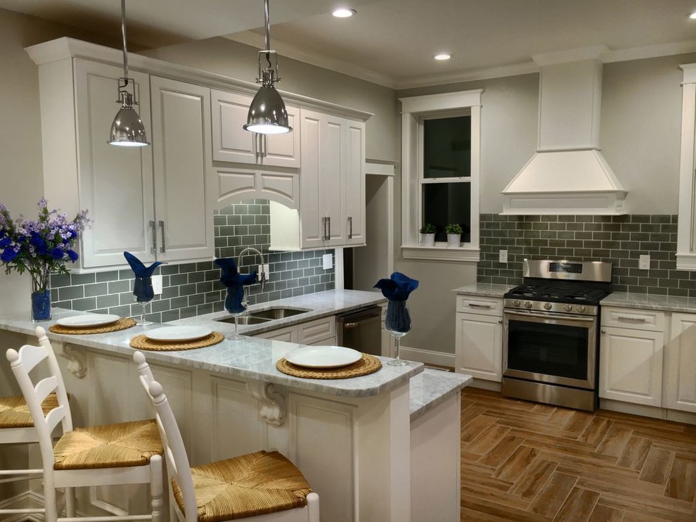 Design ideas for a traditional l-shaped eat-in kitchen in Denver with an undermount sink, raised-panel cabinets, white cabinets, marble benchtops, grey splashback, glass tile splashback, stainless steel appliances, porcelain floors and a peninsula.
