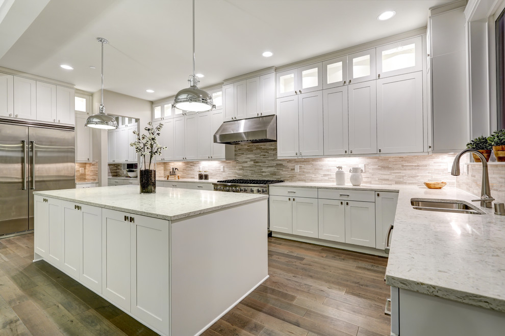 Inspiration for a large modern galley eat-in kitchen in DC Metro with an undermount sink, recessed-panel cabinets, white cabinets, quartz benchtops, brown splashback, ceramic splashback, stainless steel appliances, medium hardwood floors, with island, brown floor and grey benchtop.