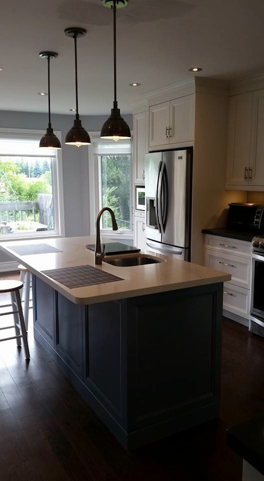 Mid-sized transitional l-shaped dark wood floor eat-in kitchen photo in Toronto with an undermount sink, recessed-panel cabinets, white cabinets, stainless steel appliances, an island, marble countertops, beige backsplash and porcelain backsplash