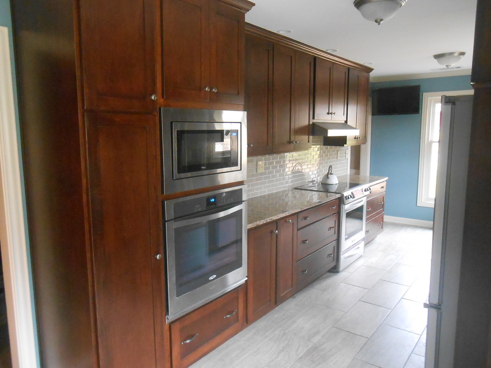 Mid-sized transitional galley porcelain tile eat-in kitchen photo with an undermount sink, shaker cabinets, dark wood cabinets, quartz countertops, beige backsplash, glass sheet backsplash, stainless steel appliances, blue walls and no island