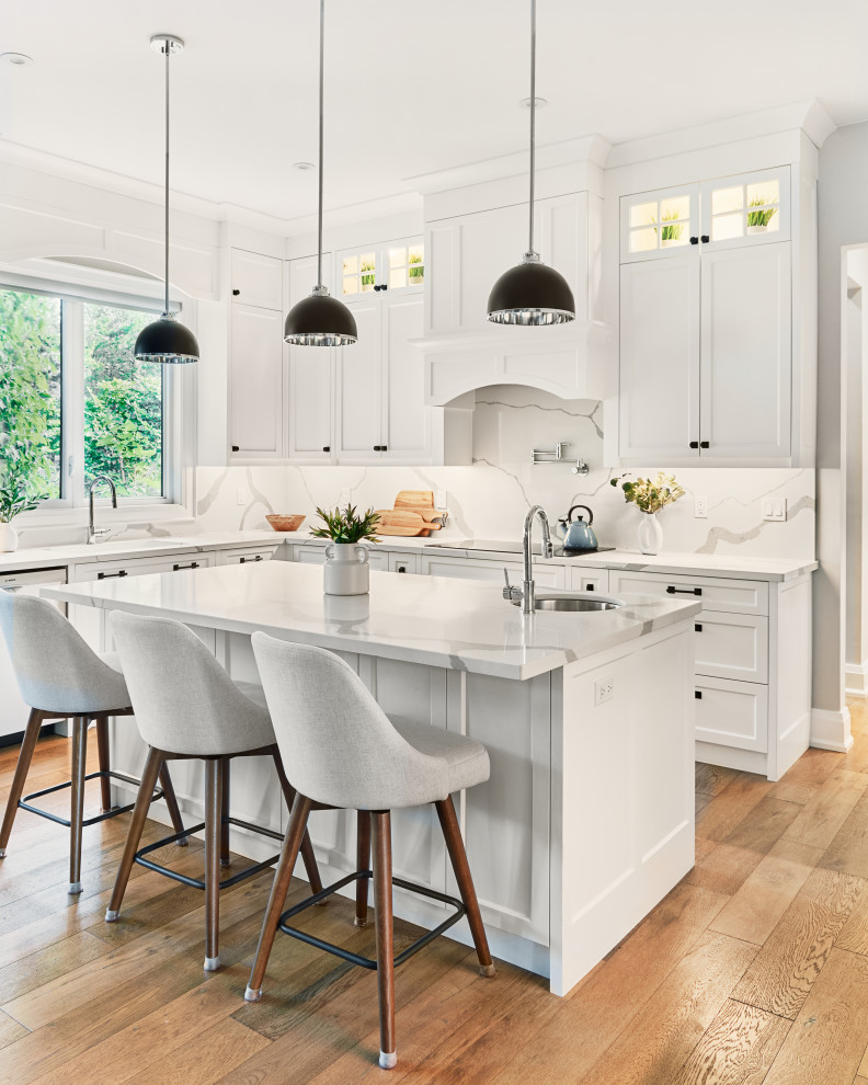 Kitchen - transitional l-shaped medium tone wood floor and brown floor kitchen idea in Toronto with an undermount sink, shaker cabinets, white cabinets, white backsplash, stone slab backsplash, an island and white countertops