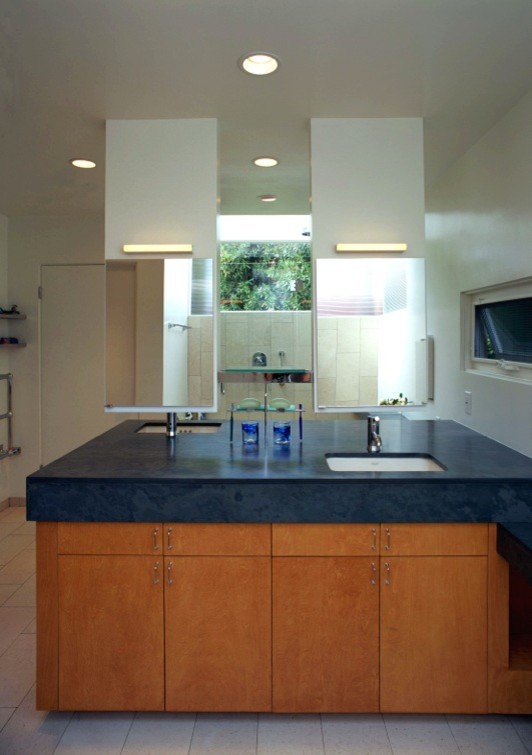 Inspiration for a mid-sized contemporary master bathroom in Los Angeles with flat-panel cabinets, medium wood cabinets, an alcove shower, white walls, porcelain floors, an undermount sink and soapstone benchtops.