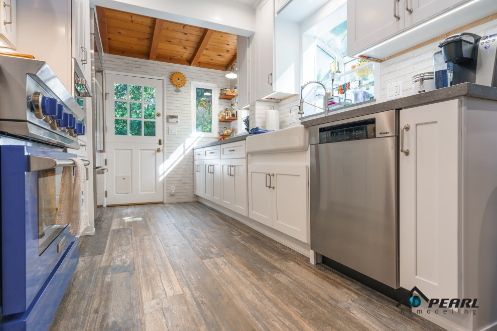 Mid-sized country galley dark wood floor, brown floor and shiplap ceiling kitchen pantry photo in Los Angeles with a farmhouse sink, shaker cabinets, white cabinets, quartz countertops, white backsplash, stone tile backsplash, stainless steel appliances, no island and gray countertops