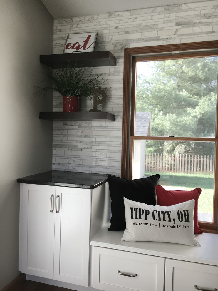 Large transitional single-wall medium tone wood floor eat-in kitchen photo with an undermount sink, shaker cabinets, white cabinets, granite countertops, multicolored backsplash, marble backsplash, stainless steel appliances, an island and black countertops