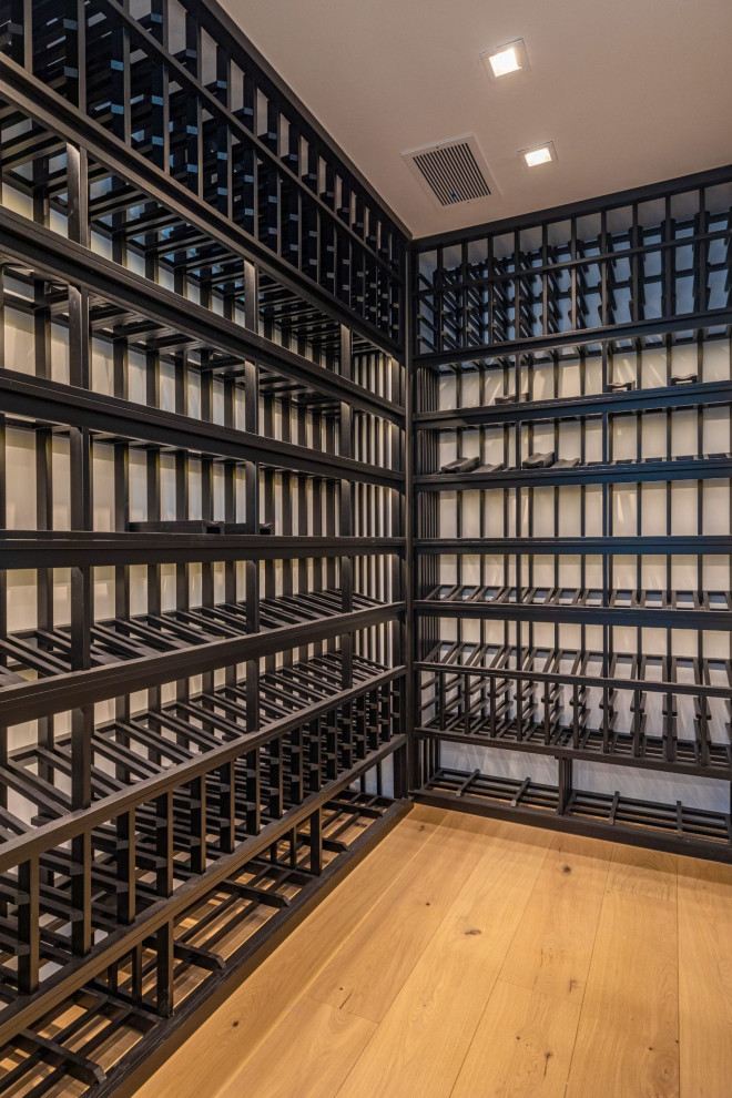 This is an example of a medium sized classic wine cellar in Los Angeles with medium hardwood flooring, display racks, beige floors and a feature wall.