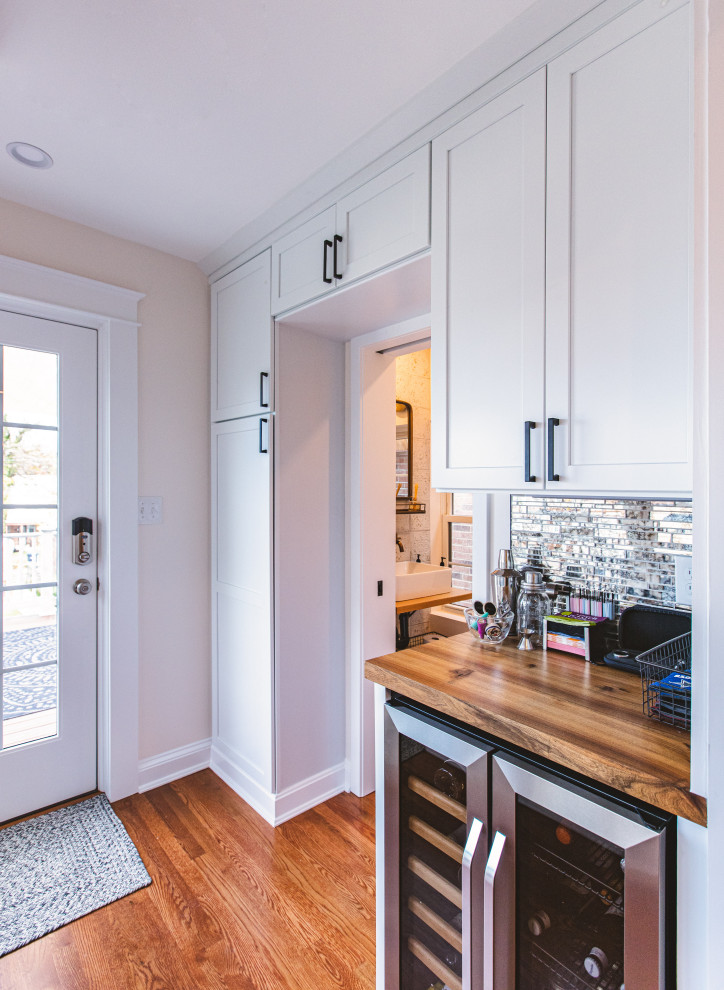Mid-sized contemporary l-shaped open plan kitchen in DC Metro with a farmhouse sink, shaker cabinets, grey cabinets, quartzite benchtops, white splashback, subway tile splashback, stainless steel appliances, light hardwood floors, with island, brown floor and white benchtop.