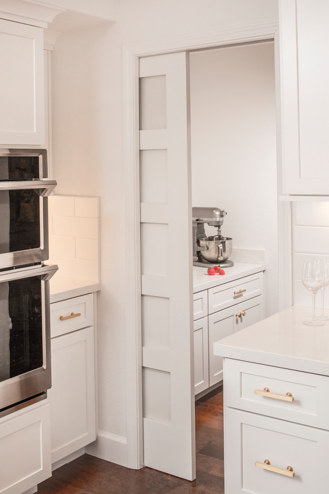 Kitchen pantry - large transitional u-shaped medium tone wood floor and brown floor kitchen pantry idea with a farmhouse sink, shaker cabinets, white cabinets, quartzite countertops, white backsplash, subway tile backsplash, stainless steel appliances, an island and white countertops