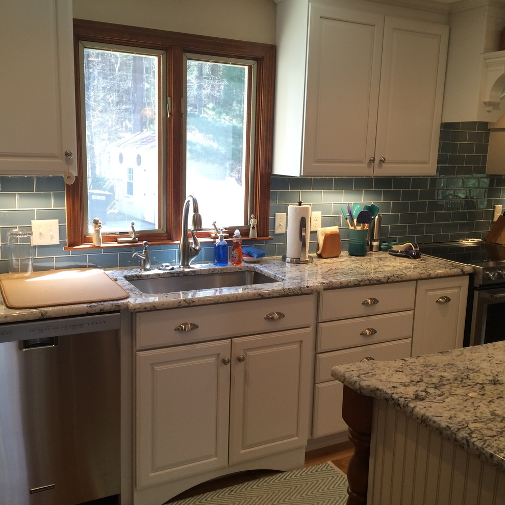 Eat-in kitchen - transitional u-shaped medium tone wood floor eat-in kitchen idea in Boston with an undermount sink, raised-panel cabinets, white cabinets, granite countertops, blue backsplash, glass tile backsplash, stainless steel appliances and an island
