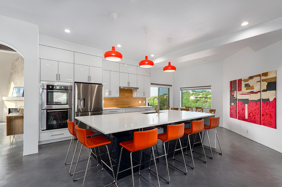Kitchen - contemporary galley concrete floor and gray floor kitchen idea with an undermount sink, flat-panel cabinets, white cabinets, stainless steel appliances, an island and white countertops