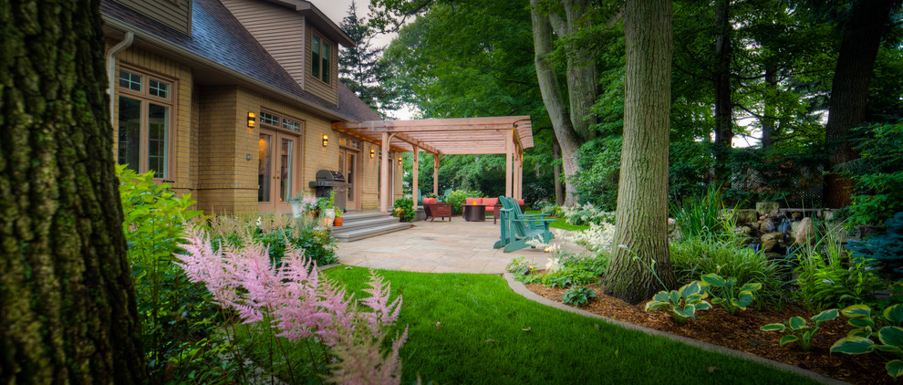 Large traditional backyard patio in Toronto with a fire feature, natural stone pavers and a pergola.