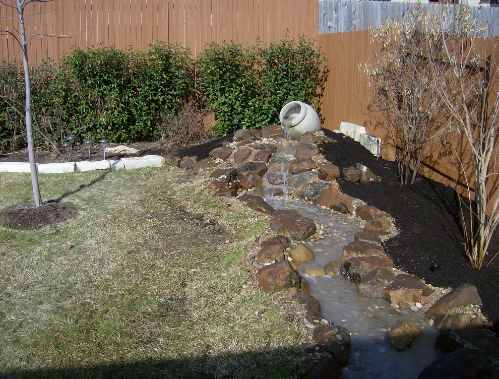 Inspiration for a large backyard partial sun garden in Austin with a water feature and mulch.