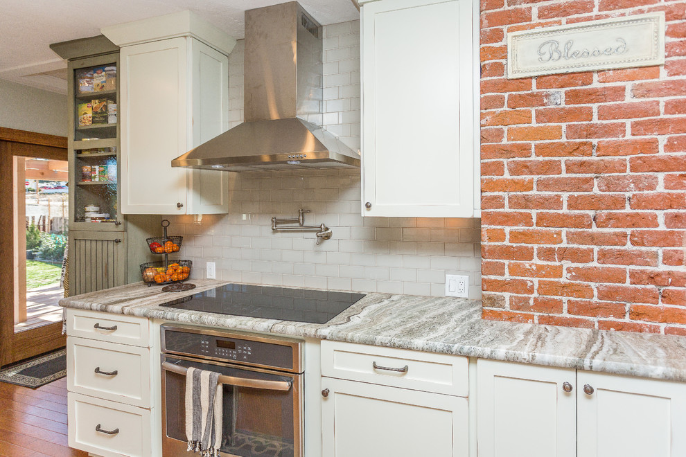 Open concept kitchen - large transitional l-shaped medium tone wood floor and brown floor open concept kitchen idea in Phoenix with a farmhouse sink, shaker cabinets, white cabinets, quartzite countertops, gray backsplash, porcelain backsplash, stainless steel appliances and no island