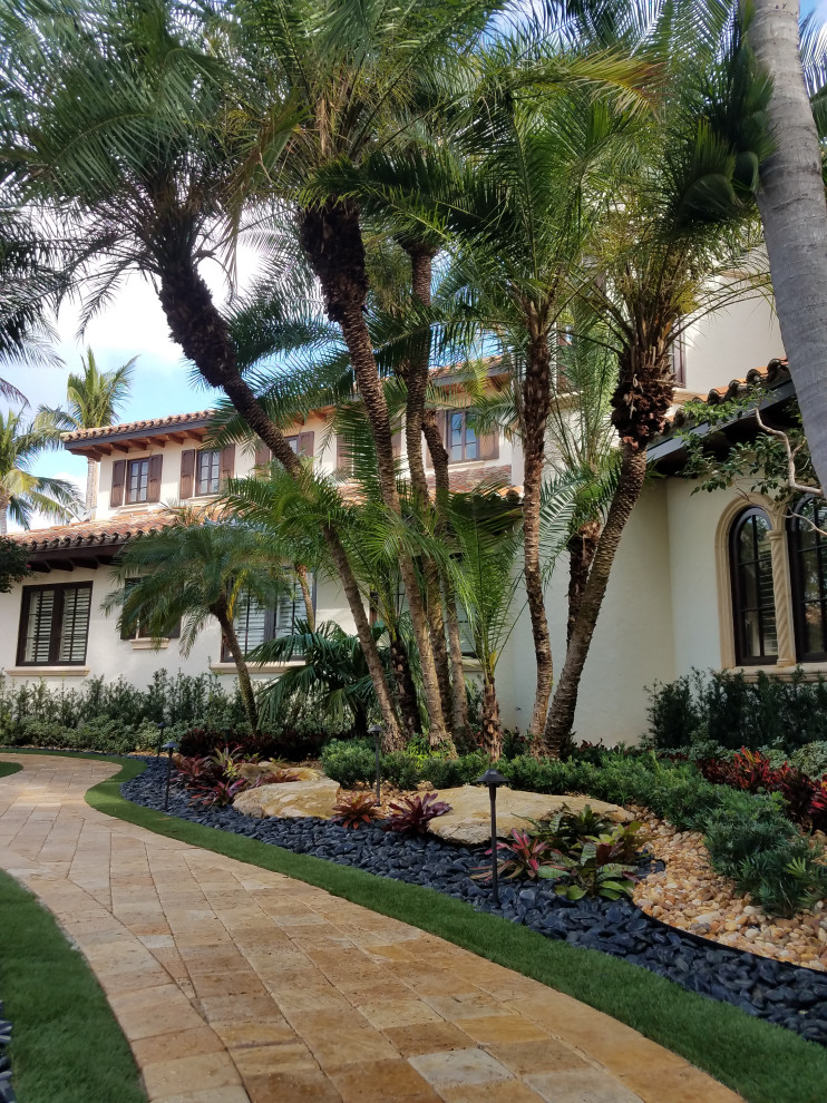 Inspiration for an expansive traditional front yard driveway in Miami with with path and river rock.