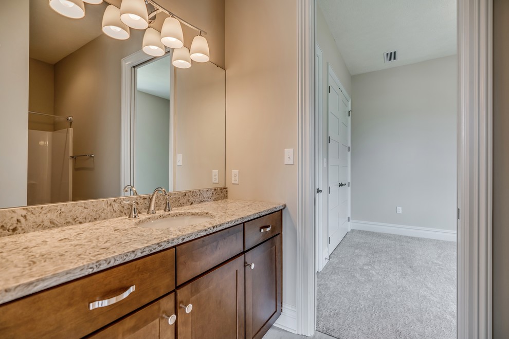 Example of a transitional kids' brown tile and ceramic tile ceramic tile and brown floor tub/shower combo design with raised-panel cabinets, medium tone wood cabinets, a two-piece toilet, gray walls, an undermount sink, granite countertops and brown countertops