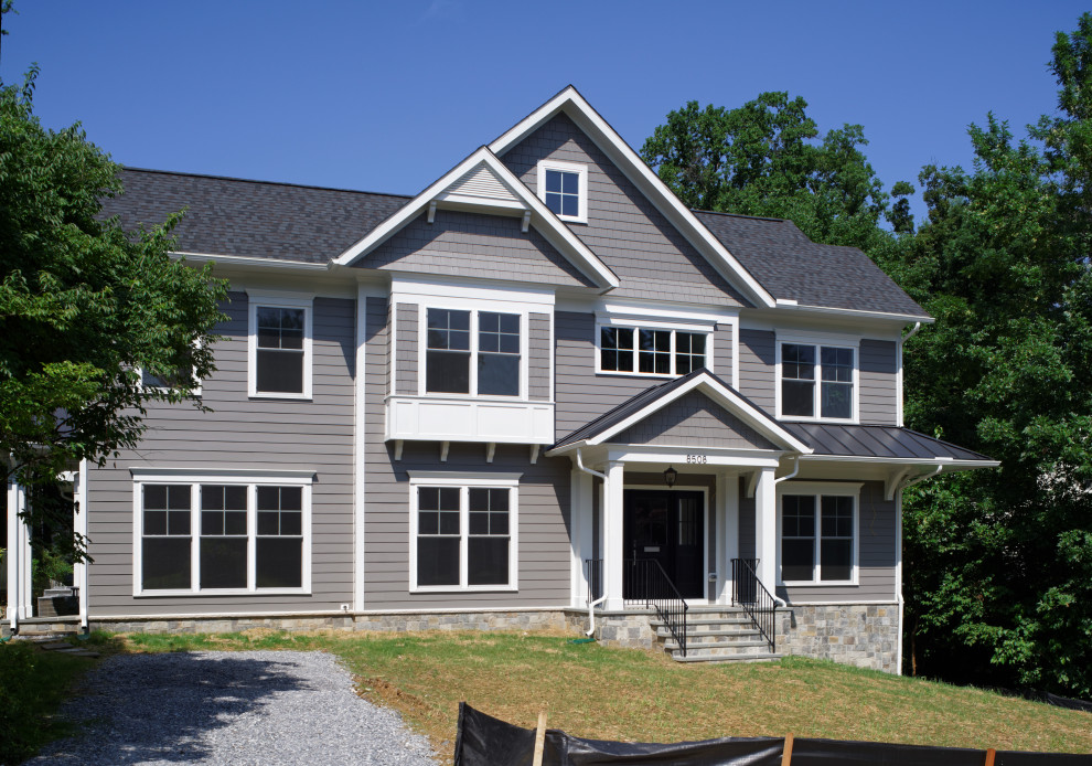Large transitional grey house exterior in DC Metro with a gable roof, a mixed roof, a black roof, clapboard siding, four or more storeys and concrete fiberboard siding.
