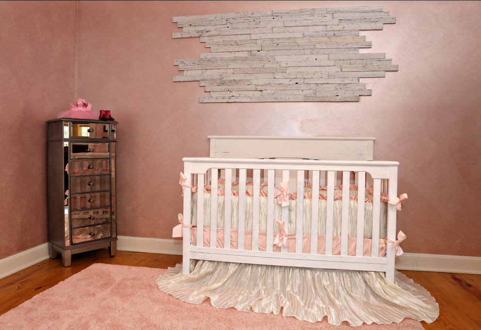 This is an example of a mid-sized traditional nursery for girls in Louisville with pink walls and light hardwood floors.