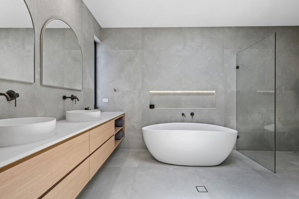 Skandinavisk inredning av ett stort vit vitt en-suite badrum, med möbel-liknande, beige skåp, ett fristående badkar, en dubbeldusch, grå kakel, porslinskakel, grå väggar, klinkergolv i porslin, ett integrerad handfat, granitbänkskiva, grått golv och med dusch som är öppen