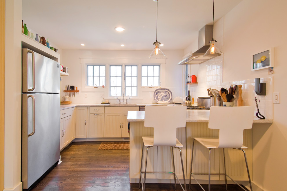 Transitional u-shaped separate kitchen in New York with an undermount sink, recessed-panel cabinets, white cabinets, white splashback, subway tile splashback and stainless steel appliances.