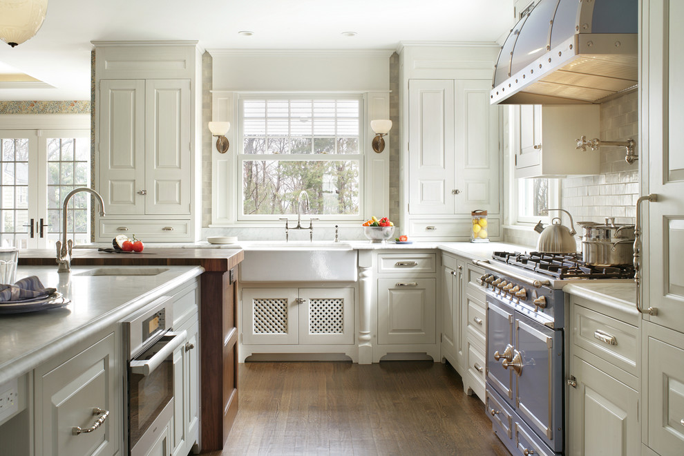 Photo of a traditional l-shaped kitchen in New York with a farmhouse sink, raised-panel cabinets, white cabinets, white splashback, subway tile splashback and coloured appliances.