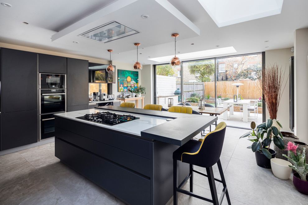 Mid-sized modern eat-in kitchen in London with flat-panel cabinets, black cabinets, with island and grey floor.