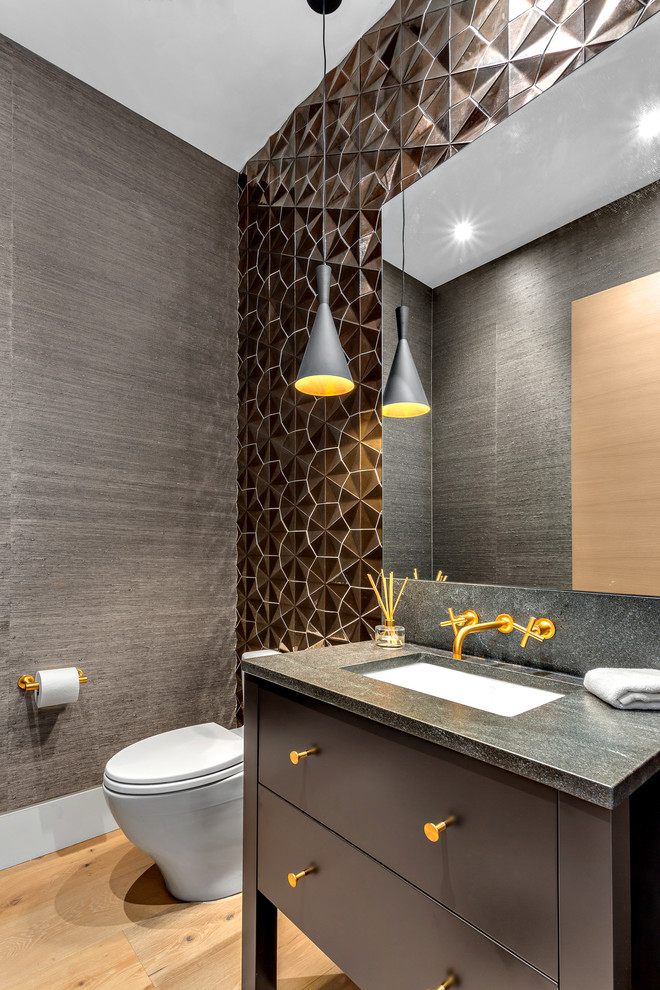 This is an example of a small contemporary powder room in Vancouver with brown cabinets, brown tile, ceramic tile, grey walls, light hardwood floors, an undermount sink, engineered quartz benchtops, grey benchtops, furniture-like cabinets and beige floor.