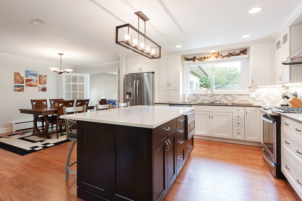 Inspiration for a large transitional l-shaped eat-in kitchen in Chicago with an undermount sink, shaker cabinets, white cabinets, stainless steel appliances, medium hardwood floors and with island.