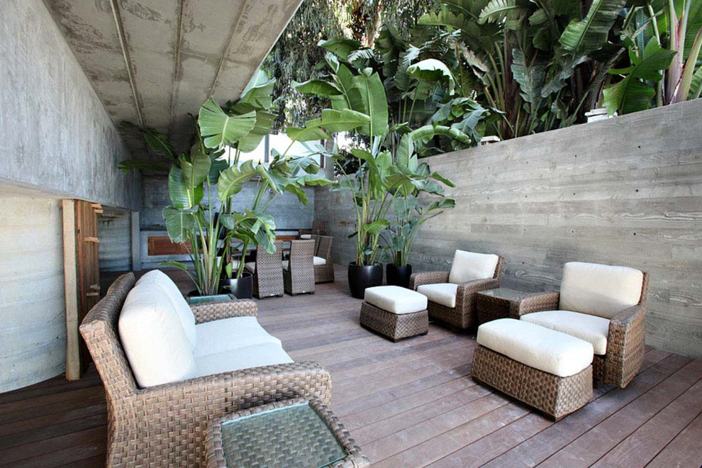 This is an example of an expansive beach style side yard patio in Los Angeles with a container garden, decking and a roof extension.