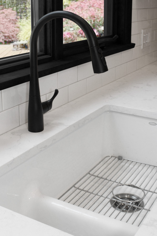 Example of a large transitional u-shaped light wood floor and brown floor enclosed kitchen design in Boston with a double-bowl sink, shaker cabinets, gray cabinets, quartz countertops, white backsplash, porcelain backsplash, black appliances, an island and white countertops